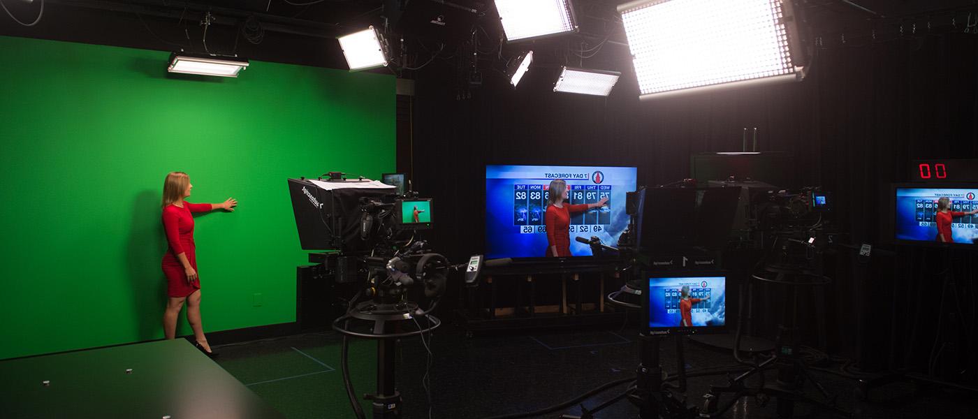 演播室里身穿红色服装的广播员正在进行气象广播